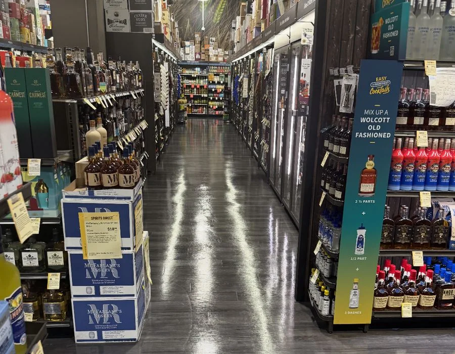 Reflective hard flooring along an aisle of wine and spirits shelves