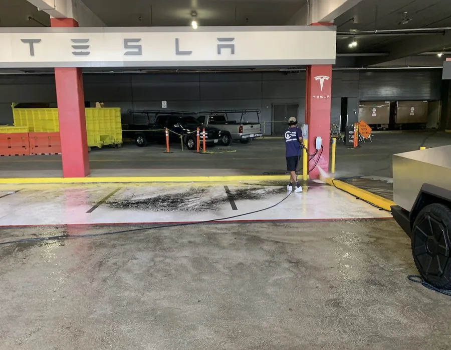 Cleaner pressure washing a concrete vehicle bay inside a parking structure